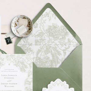May include: A green envelope with a white floral pattern liner. The envelope is folded and has a white seal on the front. The text on the invitation reads "Together with the love of their families Lydia Isabella Stephens and Jeremy Andrew Williams invite you to celebrate their wedding."