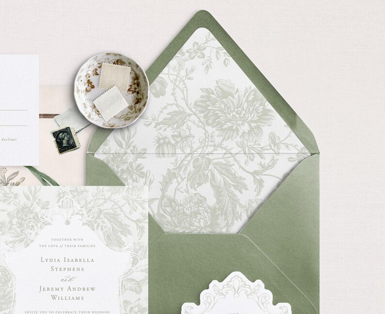 May include: A green envelope with a white floral pattern liner. The envelope is folded and has a white seal on the front. The text on the invitation reads "Together with the love of their families Lydia Isabella Stephens and Jeremy Andrew Williams invite you to celebrate their wedding."