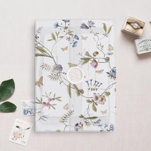 May include: A clear, floral-patterned envelope with a wax seal. The envelope is decorated with delicate watercolor illustrations of butterflies, flowers, and leaves in shades of blue, pink, and green.