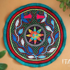 Può includere: Un arazzo da parete rotondo, colorato e ricamato con un motivo floreale. Il centro del motivo presenta un'esplosione di stelle multicolori su uno sfondo verde. L'anello esterno del motivo presenta un motivo ripetitivo di foglie blu, bianche e verdi.