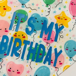 May include: White fabric with a blue and yellow pattern of balloons and stars. The text "It's My Birthday" is written in blue.