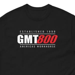 May include: Black t-shirt with the text "ESTABLISHED 1999 GMT800 AMERICAS WORKHORSE" in white and red lettering. The shirt has a crew neck and short sleeves. The text is centered on the chest.