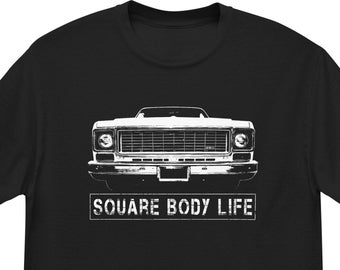 Puede incluir: Camiseta negra con un gráfico blanco de una camioneta vintage y el texto "SQUARE BODY LIFE".
