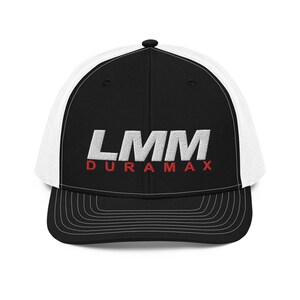 May include: Black and white trucker hat with the text "LMM DURAMAX" embroidered in white and red. The hat features a black front panel and brim, with a white mesh back. The brim has white stitching.