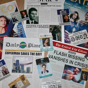 May include: A collection of newspaper clippings and magazine covers featuring superheroes, including Superman, Supergirl, and The Flash. The headlines include "Superman Saves the Day!" and "Flash Missing, Vanishes in Crisis".