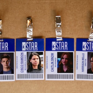 May include: Four blue and white plastic ID badges with the text "STAR LABORATORIES" and a picture of a person. The text "UNRESTRICTED ACCESS" is on each badge. The names on the badges are Barry Allen, Cisco Ramdon, Caitlin Snow, and Harrison Wells.