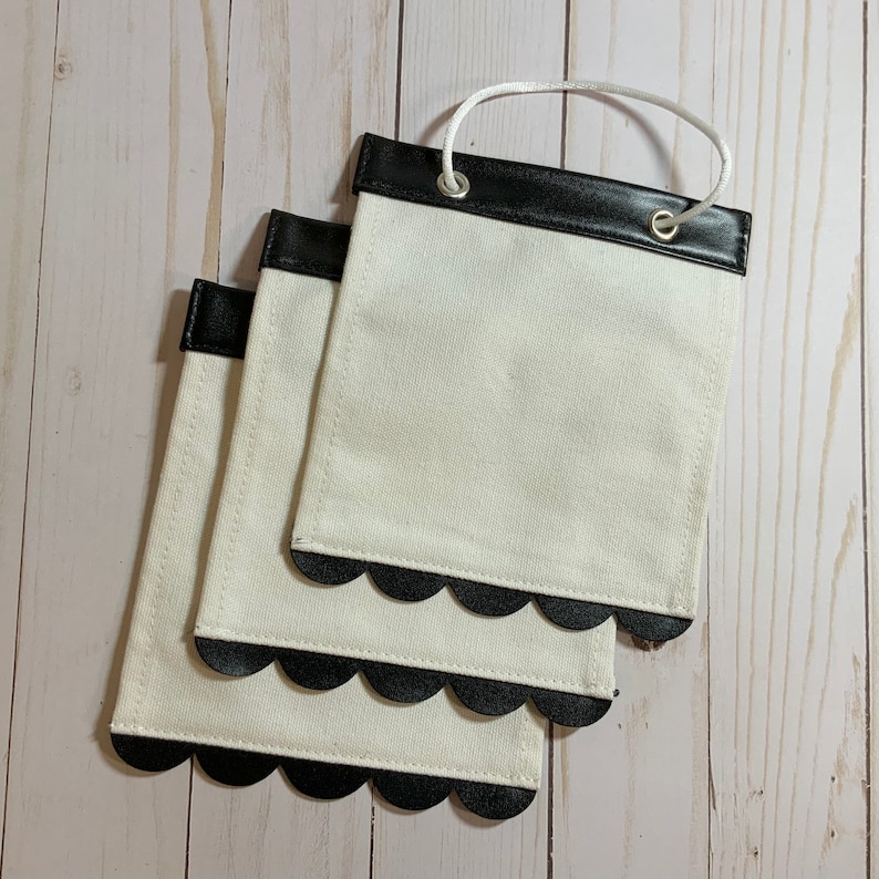 May include: Three white fabric pouches with black scalloped edges and black leather trim. Each pouch has a white string loop handle.