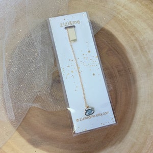 May include: Gold bookmark with a small teacup charm. The bookmark is packaged on a white card with the text "zizi&me" and "ziziandme.etsy.com".