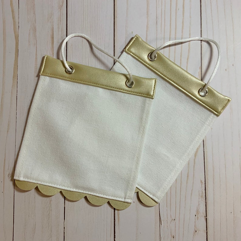 May include: Two white fabric banners with gold trim and scalloped edges. The banners have gold eyelets and are ready to be hung.