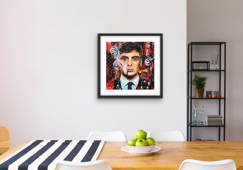 Puede incluir: Una pintura enmarcada de un hombre con cabello oscuro y traje, fumando un cigarrillo. El fondo es un dise&ntilde;o abstracto rojo y negro con humo blanco.