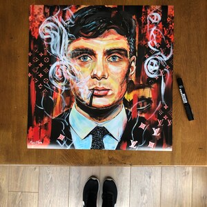 Puede incluir: Una pintura colorida de un hombre con cabello oscuro, que lleva un traje y una corbata, fumando un cigarrillo. El fondo es un patr&oacute;n rojo y negro con el logotipo de Louis Vuitton.