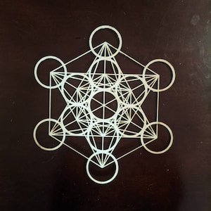 May include: A white geometric design with overlapping circles and lines, resembling a sacred geometry pattern.