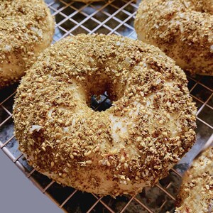 Op de afbeelding: Close-up van verschillende bagels bedekt met een royale laag sesamzaad en kruiden. De bagels zijn licht van kleur en liggen op een metalen afkoelrek. De afbeelding toont de textuur en details van de bakkerijproducten.
