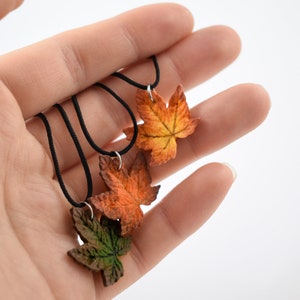 May include: Three necklaces with fall-colored leaf pendants. The leaves are made of polymer clay and are in shades of orange, red, and green.