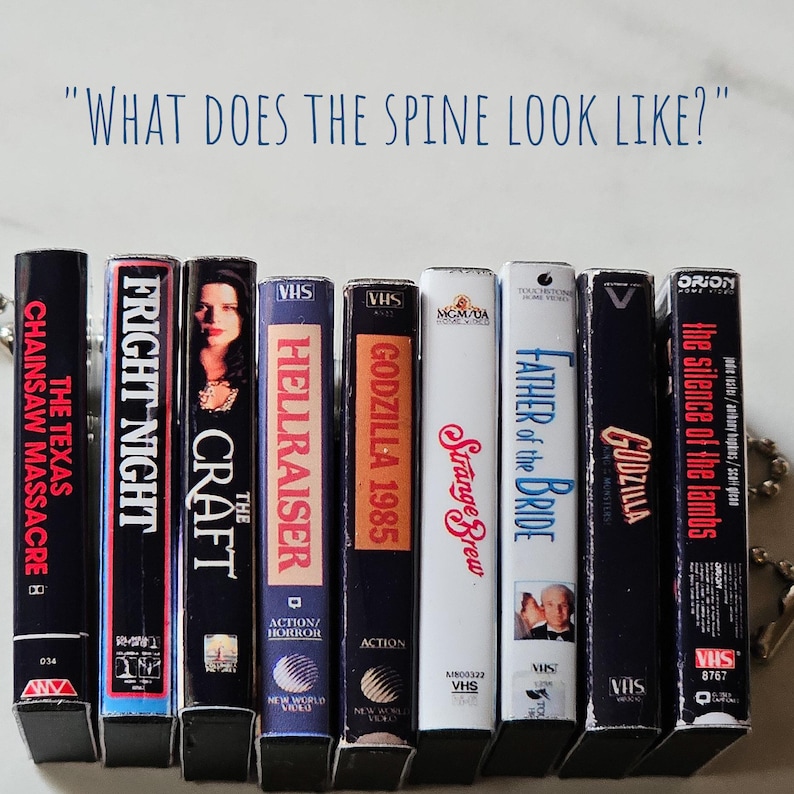 May include: A row of eight VHS tapes with various horror and action movie titles, including "The Texas Chainsaw Massacre", "Fright Night", "The Craft", "Hellraiser", "Godzilla 1985", "Strange Brew", "Father of the Bride", and "The Silence of the Lambs".