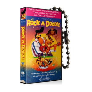 May include: A VHS tape of the animated film "Rock-A-Doodle" with a colourful cover featuring cartoon characters. The tape has a silver ball chain attached. The text on the cover includes "A Don Bluth Film" and "HBO VIDEO".