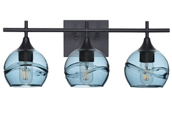May include: A black three-light vanity fixture with blue glass shades. The shades have a wavy design and are reminiscent of water.