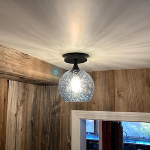 May include: A blue glass ceiling light fixture with a frosted finish and a black metal base.