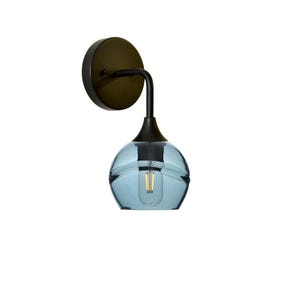 May include: A wall-mounted light fixture featuring a circular dark bronze base and a curved arm that supports a translucent, light blue glass shade. The shade has a rounded, bulbous shape and contains a single visible filament light bulb inside.