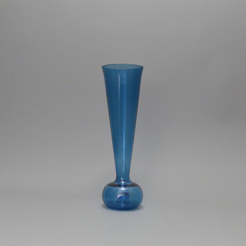 May include: A blue glass bud vase with a round base and a tall, narrow neck.