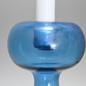 May include: A blue glass candle holder with a round, bulbous top and a slender base.
