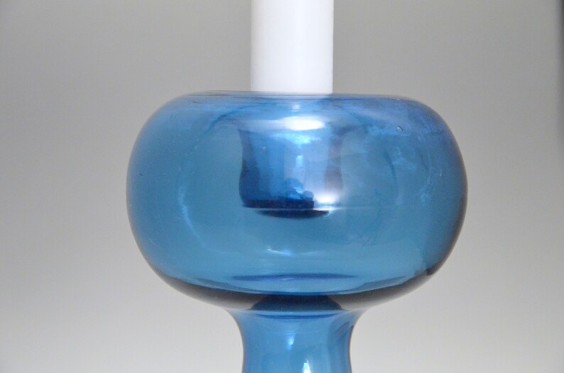 May include: A blue glass candle holder with a round, bulbous top and a slender base.