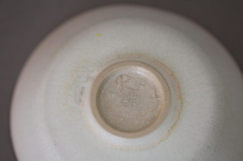 May include: A close-up of the bottom of a white ceramic bowl with a brown mark around the edge. The bowl has a circular mark in the center with the text "R.S. 41" in the center.
