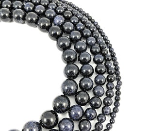 May include: A set of blue sand gemstone beads in various sizes, arranged in a circle. The beads are round and have a speckled appearance.