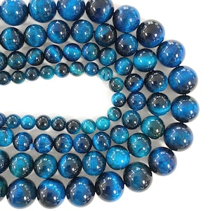 May include: A strand of blue tiger's eye beads, with a variety of sizes and shapes. The beads are smooth and polished, with a shimmering effect.