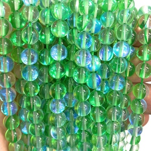 May include: A strand of iridescent green glass beads. The beads are round and have a smooth, polished finish. They are strung on a clear thread.