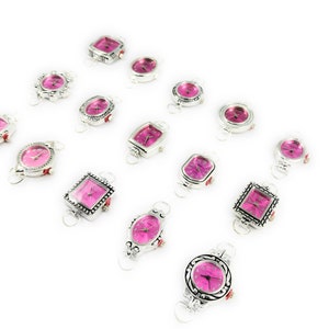 May include: A collection of 14 silver-toned wristwatches with pink faces. The watches have different shaped cases, including square, round, and oval.
