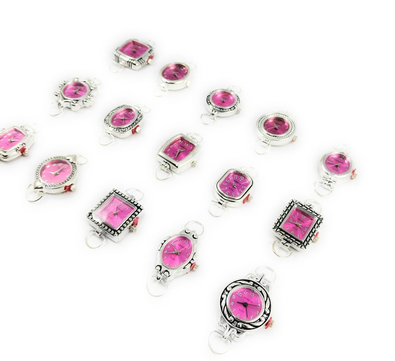 May include: A collection of 14 silver-toned wristwatches with pink faces. The watches have different shaped cases, including square, round, and oval.
