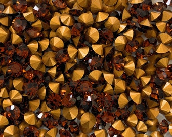 May include: A close-up image of a pile of gold and brown rhinestones. The rhinestones are faceted and have a shiny finish.