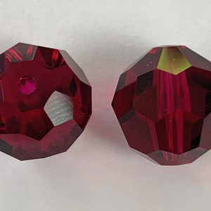 May include: Two deep red faceted glass beads with a hole in the center.