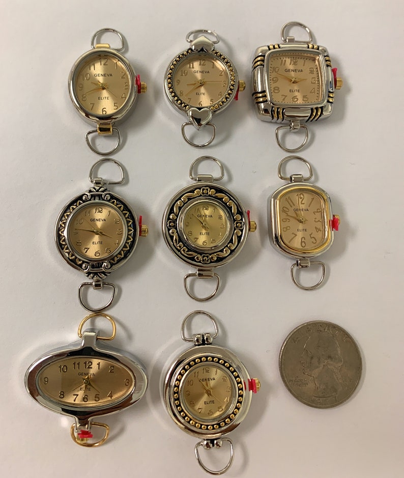 May include: Eight silver and gold tone pocket watches with different face designs. The watches have a loop at the top for attaching to a chain. The watches are arranged in three rows on a white surface.