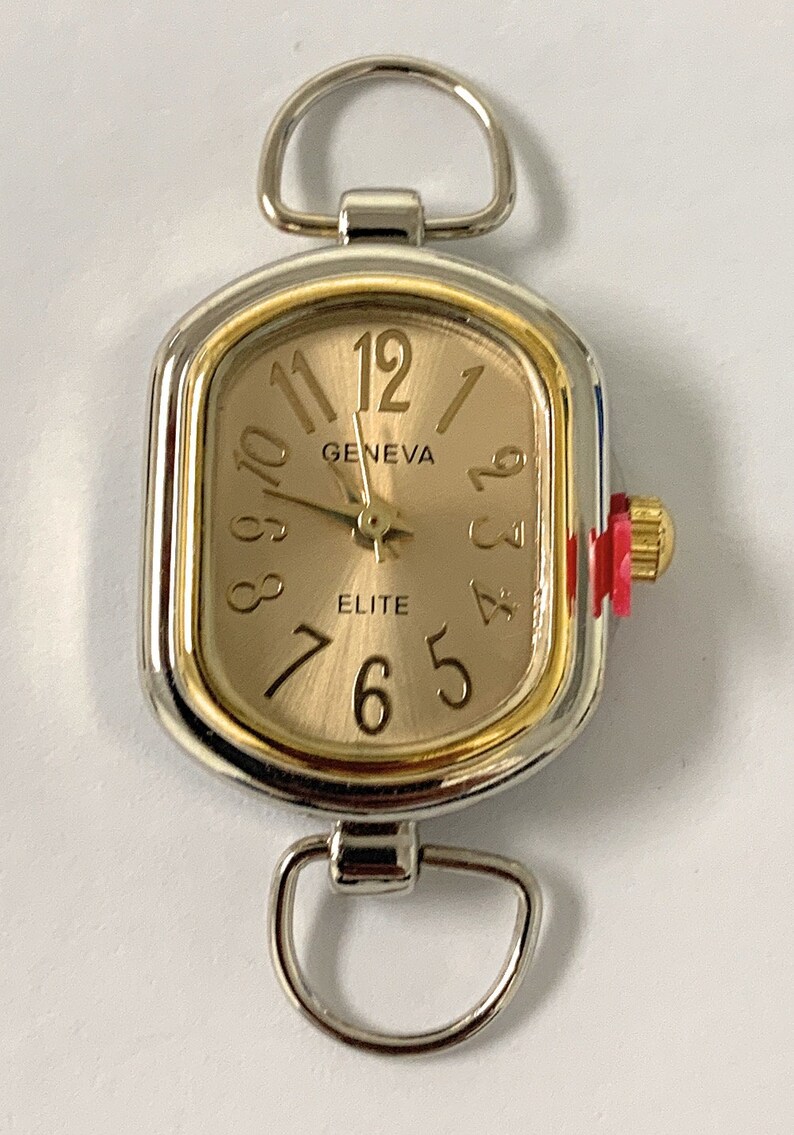 May include: A silver and gold tone watch with a rectangular face. The watch face has Roman numeral markings and says "GENEVA" and "ELITE".