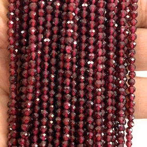May include: A strand of deep red faceted garnet beads. The beads are small and uniform in size, creating a smooth and elegant look.