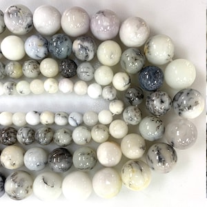 May include: A collection of white and gray opal beads with a variety of patterns. The beads are round and smooth, and they are arranged in a random pattern.