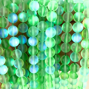 May include: A strand of round, frosted green glass beads with iridescent shimmer. The beads are strung on a green thread.