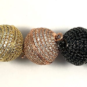 May include: Four magnetic clasps for jewelry making. The clasps are round and have a pave setting of clear rhinestones. The clasps are available in silver, gold, rose gold, and black.