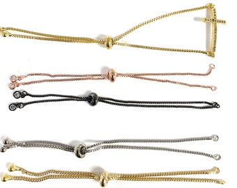 May include: Five adjustable bracelet chains with different colored metal finishes. The chains are made of a delicate, linked design. One chain features a small, sparkling cross pendant.