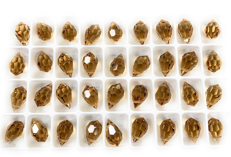 K&ouml;nnte beinhalten: Eine Schale mit 36 bernsteinfarbenen Glasperlen in Tropfenform. Die Perlen sind in einem wei&szlig;en Kunststofftablett in einem Raster angeordnet.