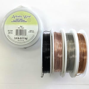 May include: Four spools of 22 gauge craft wire in black, rose gold, silver, and copper. The spools are labeled "Artistic Wire" and "22 GA 125.5 ft (38.3 m) 1/4 lb (0.11 kg)".