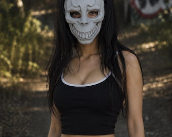 May include: A light gray rabbit skull mask with long ears and a wide, toothy grin. The mask is worn with a black cropped tank top featuring white trim, paired with black pants and a black belt with a silver buckle, creating a dark aesthetic.