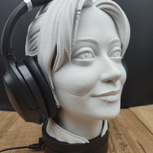 May include: A white 3D-printed head bust with short hair, holding black headphones. The bust is on a black base with a cord. The logo "MOONRABBIT" is visible at the bottom.