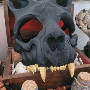 K&ouml;nnte beinhalten: Eine schwarze und goldene 3D-gedruckte Tier Sch&auml;delmaske. Die Maske hat ein detailliertes Design mit scharfen Z&auml;hnen und einem realistischen Aussehen.