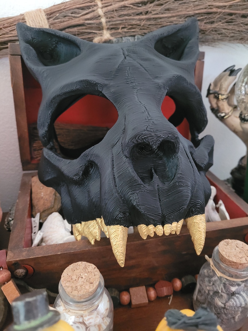 K&ouml;nnte beinhalten: Eine schwarze und goldene 3D-gedruckte Tier Sch&auml;delmaske. Die Maske hat ein detailliertes Design mit scharfen Z&auml;hnen und einem realistischen Aussehen.