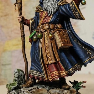 May include: A detailed figurine of a wizard in a blue robe with gold trim, holding a staff with a purple crystal and a green orb. The wizard has a long white beard and is standing on a rocky base with a lion statue.