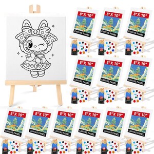 May include: A set of art supplies includes a blank canvas on a wooden easel, multiple 8" x 10" canvas panels, paint palettes, and paint tubes. The canvas features a black and white cartoon bunny design.