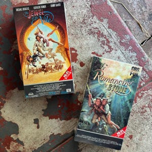 May include: Two VHS tapes of classic adventure movies. The Jewel of the Nile starring Michael Douglas, Kathleen Turner, and Danny Devito. Romancing the Stone starring Kathleen Turner and Michael Douglas.